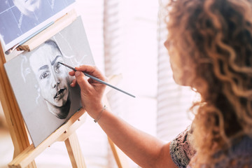 Art, creativity and people concept - caucasian closeup of woman hand painting and drawing a portrait at home in black and white - artistic leisure activity - brush on canvas to create