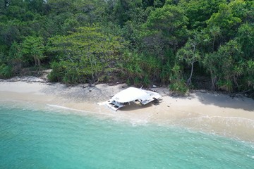 Aerial drone view part of destroyed boat on the beautiful tropical beach with lagoon sea water. Pollution, environmental problem concept
