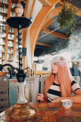 Young beautiful female smoking hookah. Smoke shisha hookah concept.