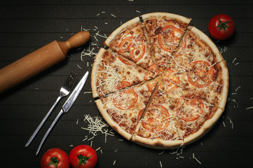 ready-made sliced pizza on a dark background top view
