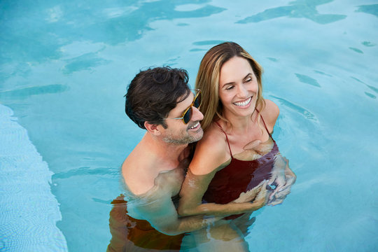 Happy couple embracing in a swimming pool - Powered by Adobe