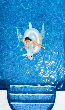 Little girl on a unicorn shaped float in a swimming pool