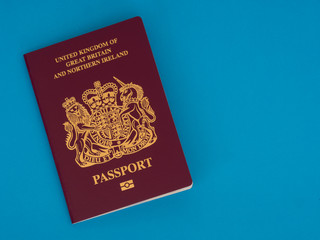 New Bergundy UK passport, no longer showing words 'European Union'. On blue surface.