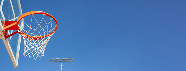 basketball hoop in front of blue sky with large copy space