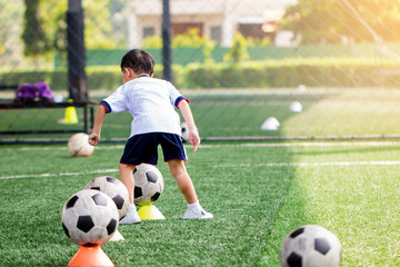 id soccer player is start training to shoot ball on marker cone to goal on artificial turf.