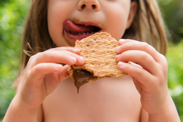 Little girl licking her lips behind a s'more