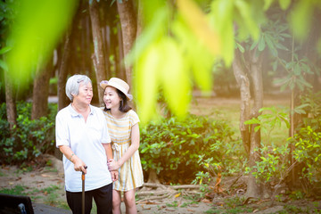 Asian little girl supporting senior woman with walking stick,happy smiling grandmother and...
