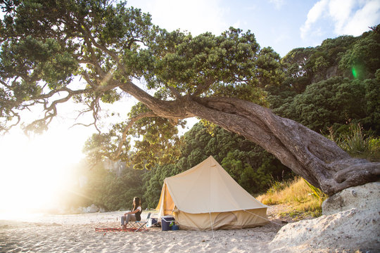 A young woman camping on a New Zealand beach