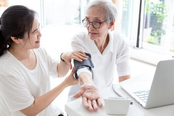 Obraz premium Female nurse checking blood pressure of a senior woman at home,asian elderly people check health,Home carer checking patients blood pressure