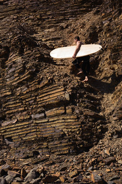 Surfer climbing up steep coast