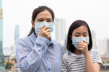 Asian mother,daughter suffer from cough with face mask protection,child,adult woman wearing face mask because of air pollution in the city, girl with medical mask;concept of pollution,dust allergies 