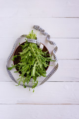 Arugula leaves are on the table, next to them is a flexible meter.