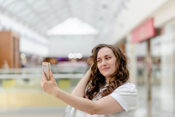 Young woman with phone in her hand making selfie. Portrait, happy smile, beauty and technology concept