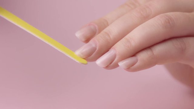 filing nails with yellow with nail file emery board