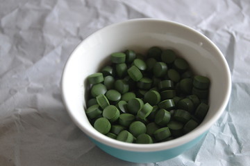 spirulina and chlorella  tablets on the light background. green tablets i
