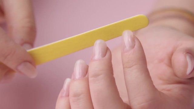 closeup woman filing her nail with yellow emery bard