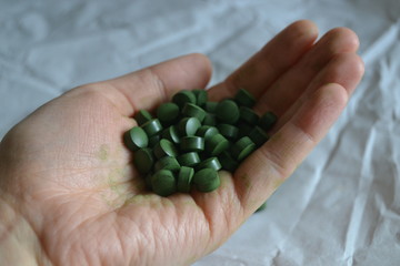 spirulina and chlorella  tablets on the light background. green tablets i