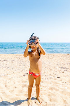 Small girl adjusting her schnorchel and goggles at the beach