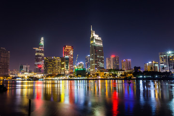 Fototapeta na wymiar Ho Chi Minh City, Vietnam - May 7, 2019 : Riverside City at nightclouds in the sky at end of day brighter coal sparkling skyscrapers along beautiful river in Ho Chi Minh City, Vietnam - Image