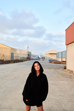 Beautiful girl in black hoodie with arms in pockets.