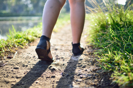 Woman's feet hiking on a path through rice fields
