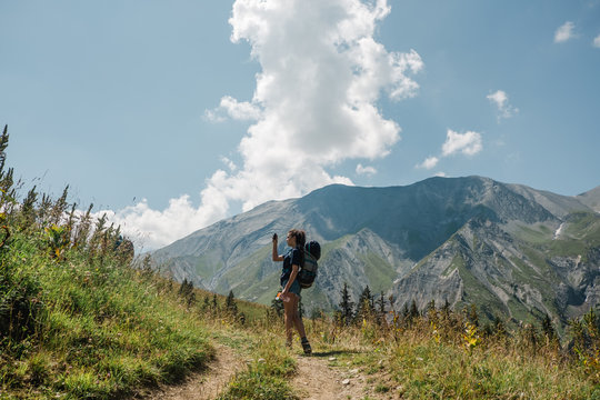 teenage girl with backpack  on a hike in the Alps, she is taking photos