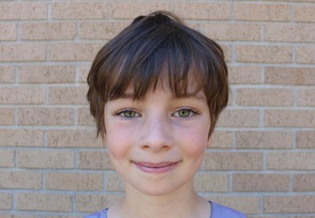 Face of young child with stunning hazel eyes, short brown pixie hair and dimples