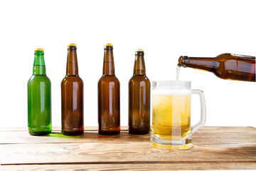 Glass and bottle of beer with no logos on wooden table isolated copy space, bottle mock up. Beer bottle studio shot with cap isolated.