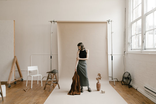 behind the scenes of model standing on backdrop paper in photo studio with props around