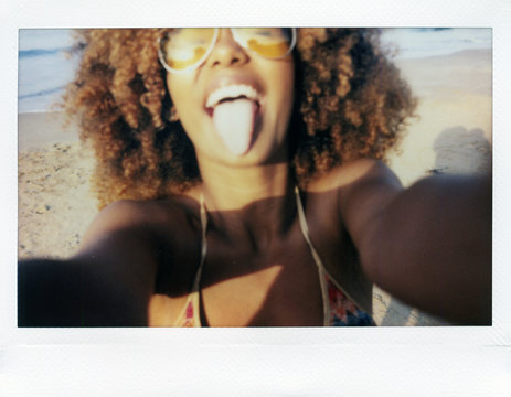 Playful woman showing tongue on instant shot