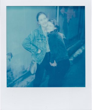 Vintage polaroid of two young adult female siblings hugging in urban setting