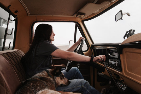 young woman driving stick shift in old pickup