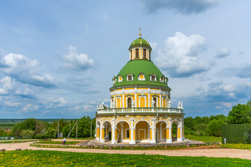 Church of the Nativity of the Virgin in Podmoklovo, Russia. Spring day with a dramatic sky. Flowering dandelions.