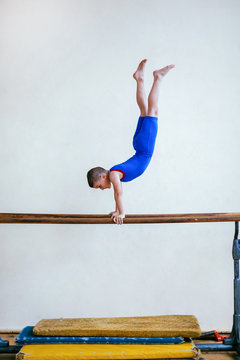Gymnastics, young boy practicing on parallel bars