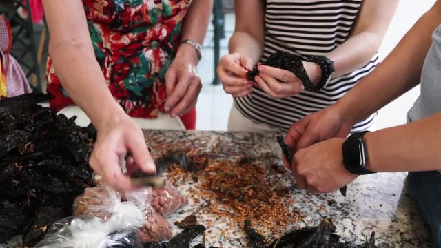 Panoramic view, from left to right. Side View. Women cleaning and removing seeds from chile. Women making Mole in Puebla Mexico. North America.  Cooking Traditional recipe