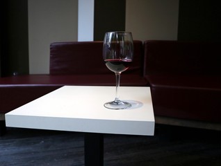 A red wine glass on a white table of a lounge bar. Background for copy space 
