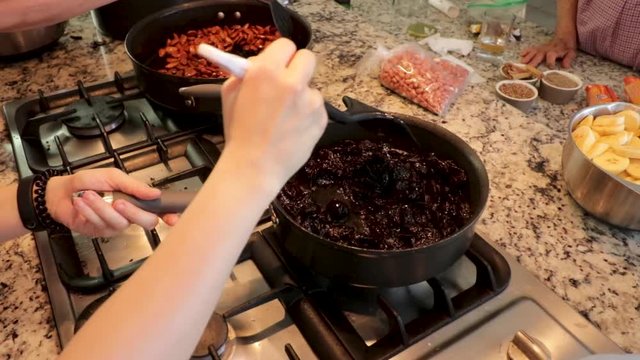 Side View. Woman frying and mixing plums in the pot. Women making Mole in Puebla Mexico. North America.  Cooking Traditional recipe