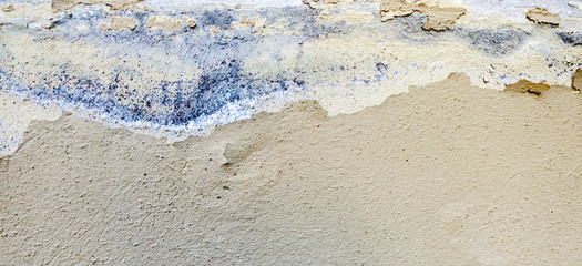 Old weathered painted wall background texture. White dirty peeled plaster wall with falling off flakes of paint.