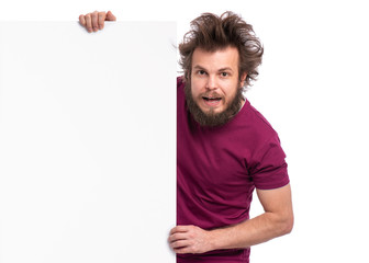 Crazy bearded Man with funny Haircut showing empty blank signboard with copy space. Smiling guy peeking out from behind big white banner, isolated on white background.