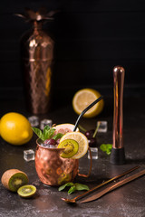 Exotic cocktail in copper mug (variation of Moscow mule) on the black stone background. Selective focus. Shallow depth of field.