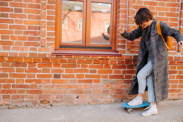 Young woman walking on the street holding skateboard. lifestyle photo.