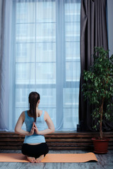 a young girl does yoga on the mat in the studio with her hands folded in a prayer pose with your hands behind your back. soft focus and rear view