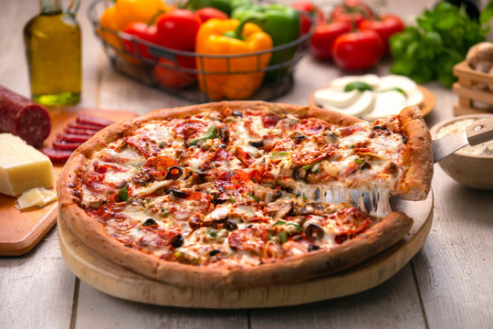 Delicious supreme pizza, deluxe toppings loaded with extra fresh ingredients, stringy cheese lifted slice
