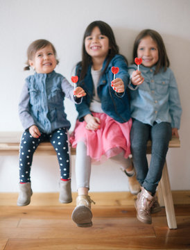 Little girls holding heart lollipops