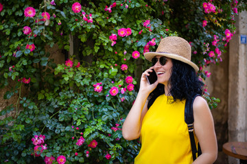 A Cheerful woman is using smarthphone in front of roses , she is typing a message or looking at social media