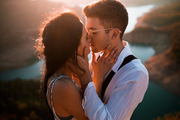 Beautiful young couple in love kissing and touching their faces on the mountain
