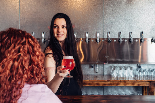 Female bartender serving craft beer at a micro brewery bar