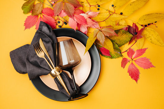 Festive table setting with Bright Autumn leaves on orange background. Flat lay, top view, copy space
