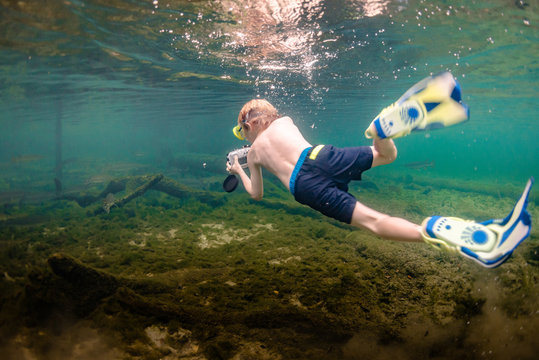 Boy diving underwater photographs fish in shallow freshwater Florida river