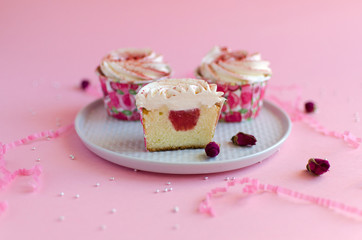 Strawberry cupcakes on white plate on pink background decorated with rosebud